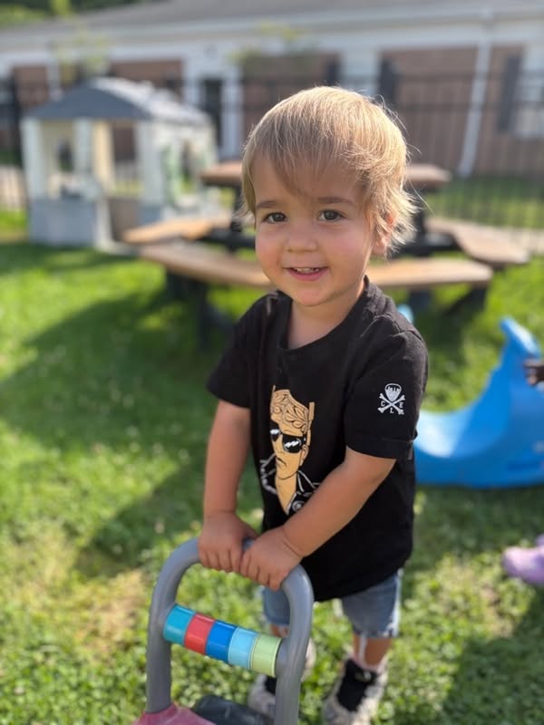 A smiling Wild Roots toddler enjoying outdoor play